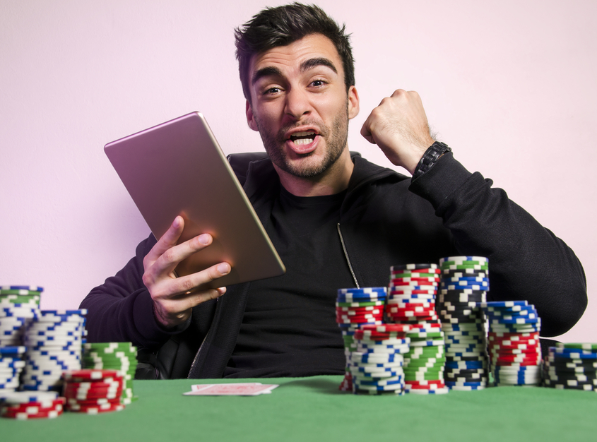 Мужчина сидит за столом для игры в покер с планшетом в руках