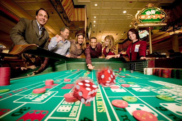 Дамы в вечерних платьях и строго одетые мужчины играют в крэпс в престижном казино vip-уровня