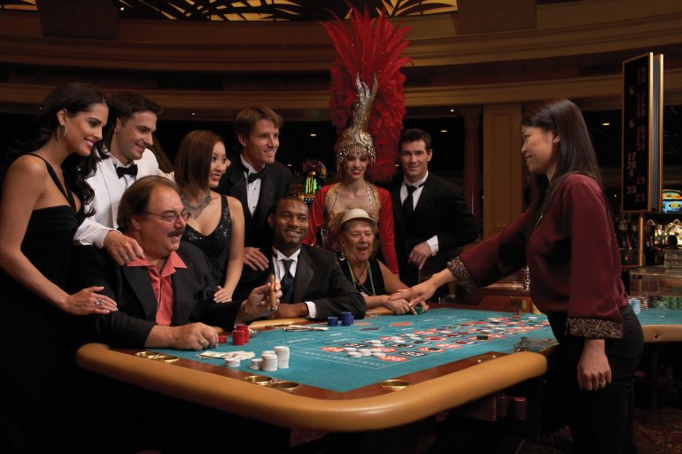 Элитные игроки разных национальностей играют в казино в компании приветливой девушки крупье