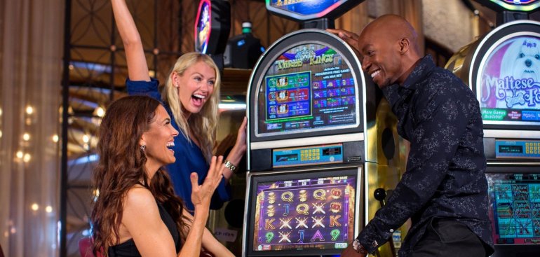 Блондинка, брюнетка и темнокожий парень радуются своей победе на игровом автомате