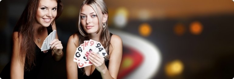 Двое дилерш казино, рыжая и блондинка, позируют с картами в руках