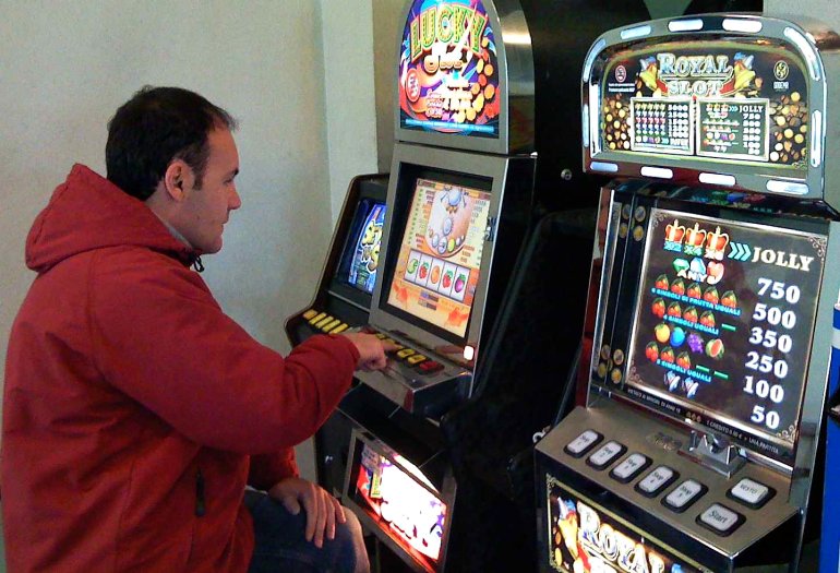 Мужчина в красной куртке играет в игровой автомат
