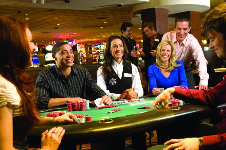 Веселые люди разных национальностей развлекаются и выпивают за игрой в дорогом казино Лас-Вегаса