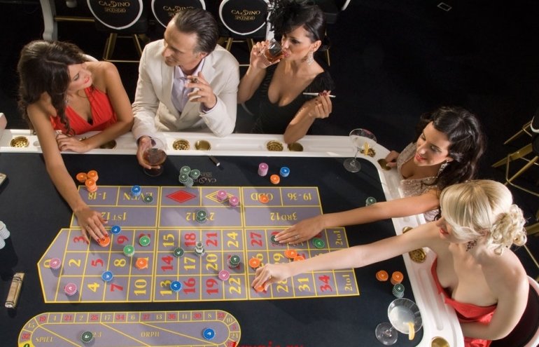 Мужчины и женщины играют в рулетку в элитном казино