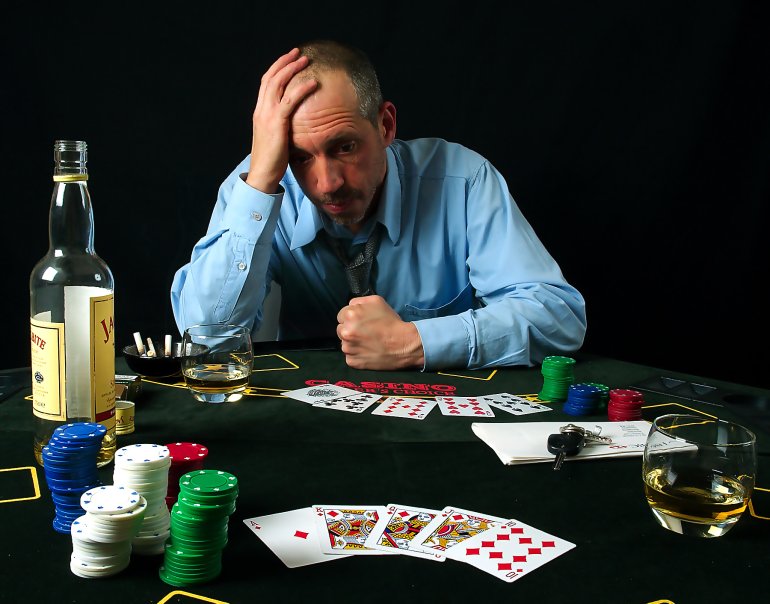 азартный игрок за столом с картами и бутылкой