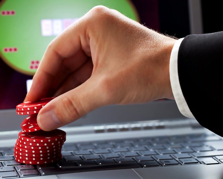Рука стопка красных фишек и покер онлайн на ноутбуке