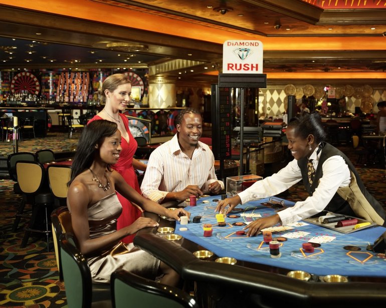 Темнокожая пара и европейская девушка играют в блэкджек против дилера в казино Sun City Hotel Casino