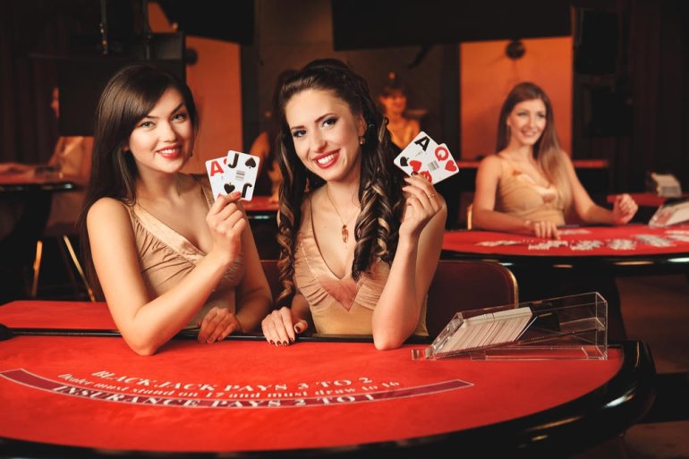 Две красивые девушки-крупье демонстрируют карты для игры в блэкджек